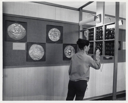 Woman examines a coin, Scripps College