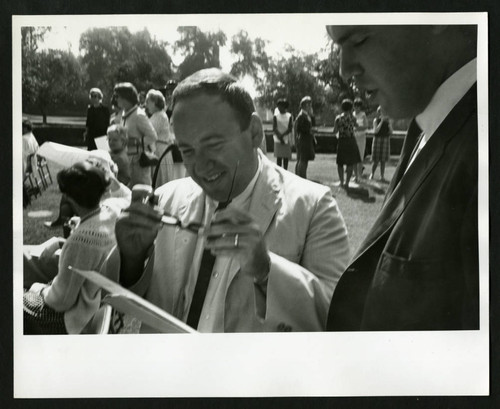 Two men reading the program for the Drake Wing Dedication, Scripps College