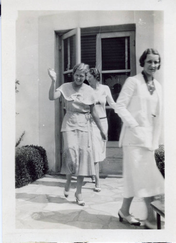 Three women exiting a door