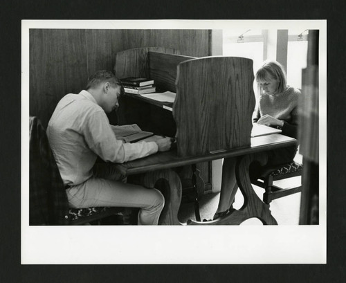 Two students doing homework at a partioned desk in Denison Library, Scripps College