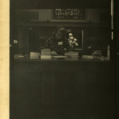 Student librarian checking in books in Denison Library, Scripps College