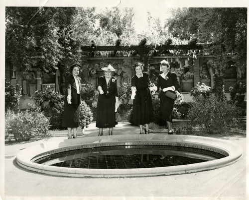 Four Scripps College trustees throwing coins into a fountain