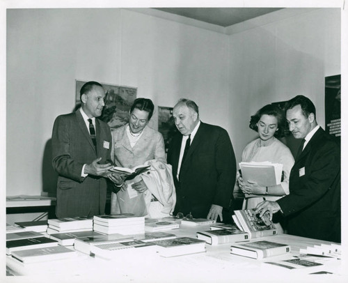 Individuals standing near a table of books, Pomona College