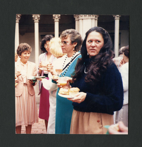 Colleagues mingling and eating cake at Betty Merfeld's retirement party, Scripps College