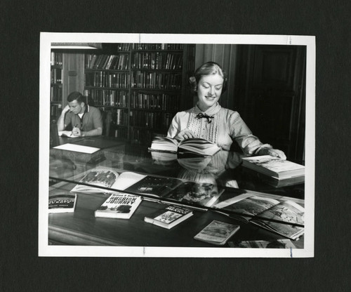 Scripps student reading on top of a display case in Denison Library, Scripps College