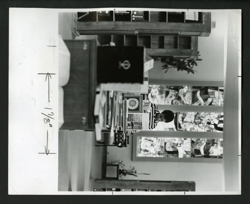 Student reading behind a bookshelf in Denison Library, Scripps College