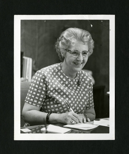 Dorothy Drake doing paperwork at her desk, Scripps College