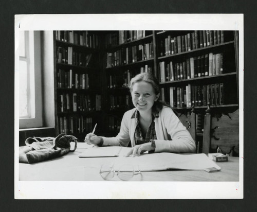 A Scripps student smiles as she does her homework at a table in Denison Library, Scripps College