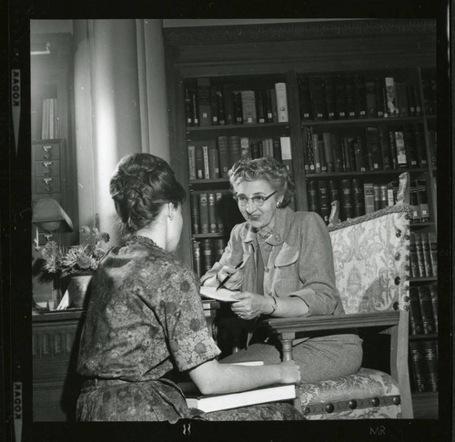 Dorothy Drake discusses a book with a student in Denison Library, Scripps College