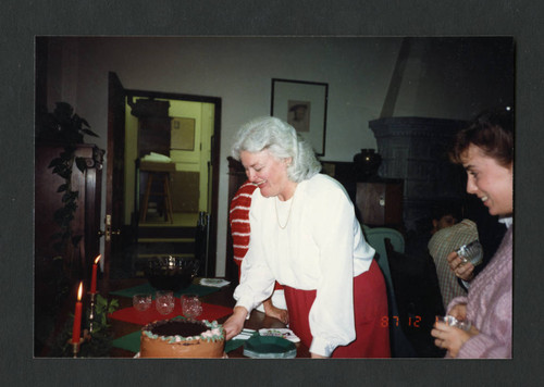 Judy Harvey Sahak cutting cake at Denison Library's Christmas Tea, Scripps College