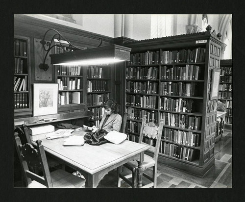 Scripps student diligently reading at a table in Denison Library, Scripps College