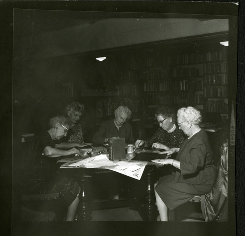 Librarians stamping books together in Denison Library, Scripps College