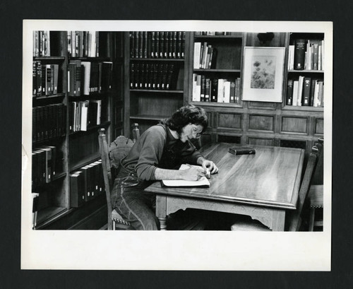 A man writing at a table in Denison Library, Scripps College