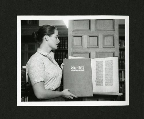 Student librarian reshelving the Gutenberg Bible in Denison Library, Scripps College