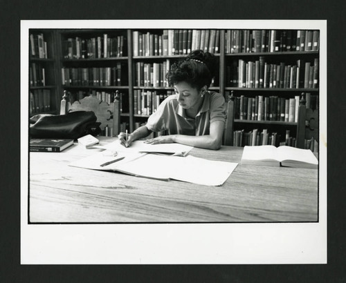 Scripps student annotating a paper at a table in Denison Library, Scripps College