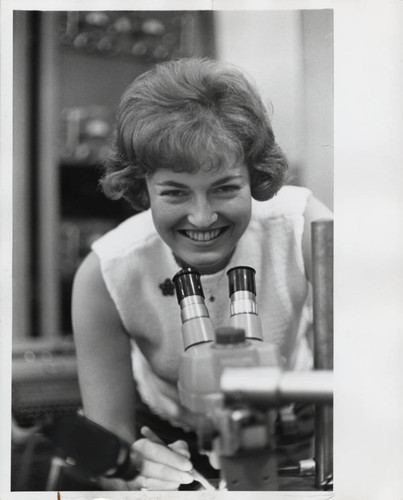 Woman at smiles over her microscope, Scripps College