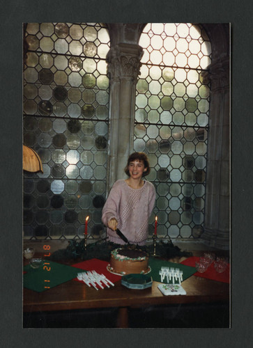 Student cutting cake at Denison Library's Christmas Tea, Scripps College