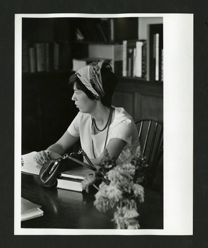 Distrait woman sitting at a table in Denison Library, Scripps College