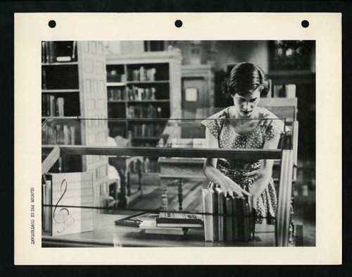 Slocum Prize contestant arranging books in an exhibit in Denison Library, Scripps College