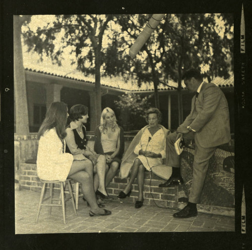 Three students listen to a woman being interviewed, Scripps College