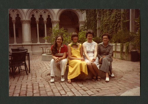 Four Denison Library staff members sitting outside Denison Library, Scripps College