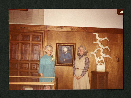 Dorothy Drake and Judy Harvey Sahak smile by Dorothy's portrait, Scripps College