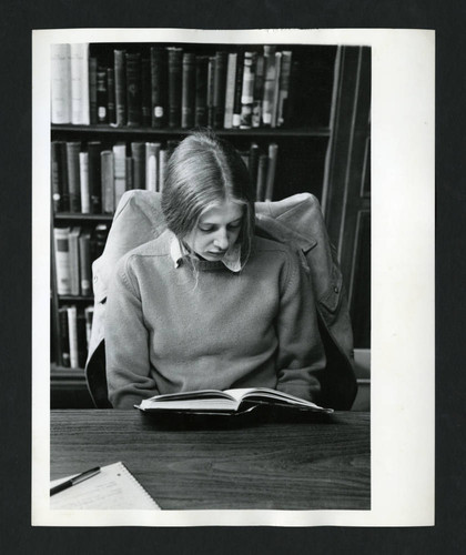 Solitary Scripps student reading at a table in Denison Library, Scripps College