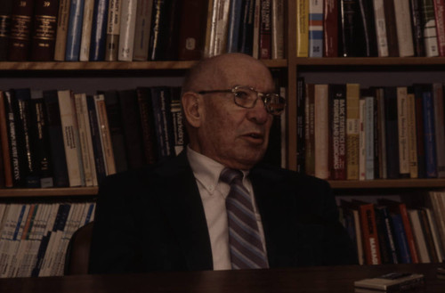 Peter Drucker sits in front of a bookshelf