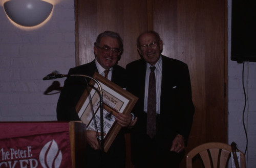 Peter Drucker standing next to an individual