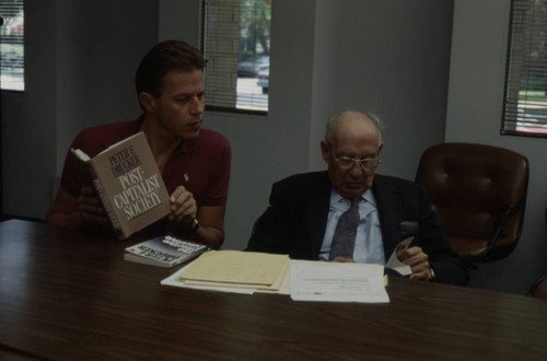 Peter Drucker sitting next to an individual holding "Post-Capitalist Society"