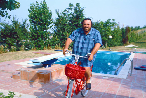 Luciano Pavarotti on bicycle in front of pool