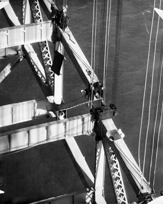 [Workers positioning a large steel structure during construction of the San Francisco-Oakland Bay Bridge]
