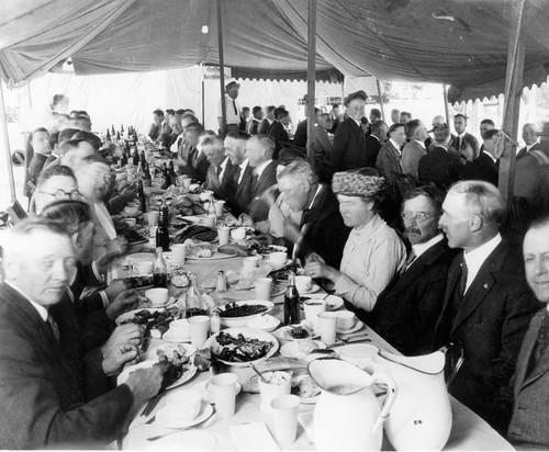 Men and women having a meal under a tent