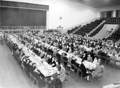 People seated at tables in an assembly hall at Grange convention