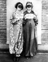 Two masked women in costume holding signs