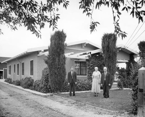 Three people in front of a house