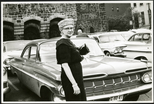 Charles Protzman's wife standing in a parking lot, 1961-05