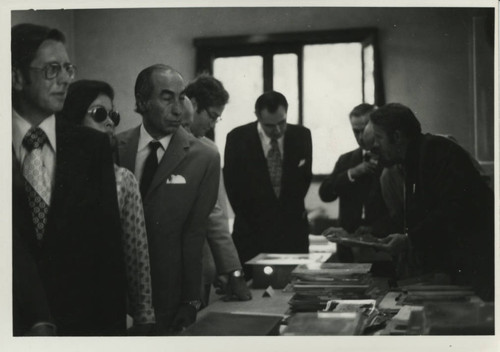 Dignitaries crowd around table with codices during Henry Kissinger's visit to the Coptic Museum