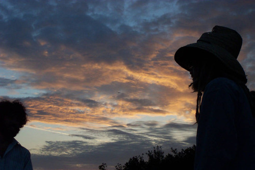 Silhouette of person wearing hat set against clouds