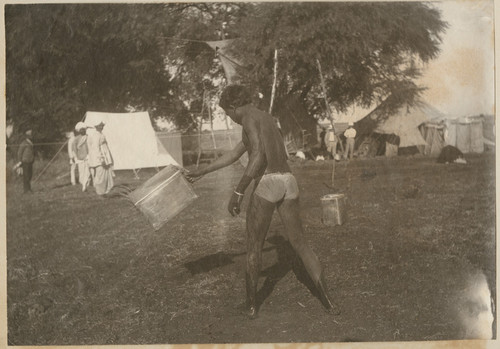 [Indian laborer watering the ground in front of Camp Pierson, Wangi, India]