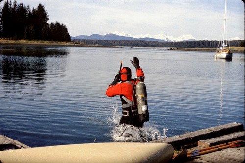 Drysuit diver jumping into a bay