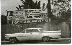 Car parked below political banner, 1960s