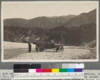 Mitchell and car in Santa Inez River near Mono ranger station, Santa Barbara County, California. The road has always been too near the creek and had always washed out every spring. We forded the river 6 times in 4 miles. The Forest Service is now (1916) constructing a good road back from the river, desiring to make summer home sites accessible. Chaparral typical of lower Santa Barbara Forest. May, 1916