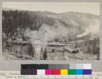 Penman Peak Lumber Company showing a sawmill and yards. Mill uses a dry landing; logs are taken to the landing by means of tractors and rolled over the skid logs into a chute, then dragged into the mill. The mill was built on the edge of their timber, just below the Highway (see also #3623) and yard space is limited (see also #3625)