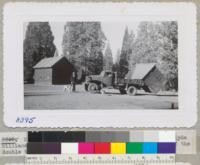 Moving day at Whitaker's Forest October 1948. Clyde Williams and Otto Browning use Army truck to move one of the double toilet buildings. "The Barn" in the background