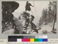 6 Califoresters riding in a box (see #3692) over the tramway of the Spanish Peak Lumber Company near Camp Califorest. On the other wire is shown a package of lumber headed toward the storage yard at Gray's Flat, traveling away in the picture. July, 1926