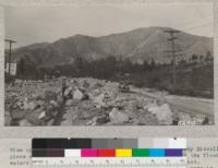 View of La Crescenta Boulevard looking towards the Harvey Bissell place with the burned area in the background from which the flood waters came. Note the mass of boulders left in the street. 1934. Metcalf