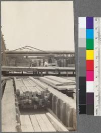 Showing method of piling lumber from sorting table. This section of table is between span of travelling crane (supports on left shown in photo). Lumber is handled in units of about 800'-1000' each; each unit being made up in bins as shown in foreground. When a bin is full and unit is this large enough, crane carries off the unit and piles it somewhere along the yard between the crane runway. Union Lumber Company, Ft. Bragg, California. May, 1920. E. F