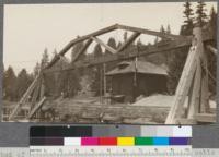 Method of unloading logs from cars. Note hook and cable suspended from truss. Track (not visible in photo) inclines toward water at the truss. Northwestern Lumber Company, near Willits, California. April, 1920, E.F