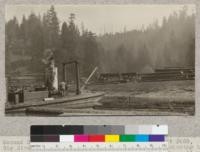 Second Growth Redwood Cutting Experiment, Project #688, Big River, Mendocino County, California. View showing how second growth logs are pulled from the cars to the roll-way. The stern wheel river barge is equipped with a drum which was pressed into this service. This barge is used for towing rafts of logs from the dump to the mill and for bringing back heavy supplies. E. Fritz, May 1923